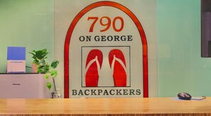 A reception desk with a sign indicating room number 790 on George, labeled as a backpackers' room.