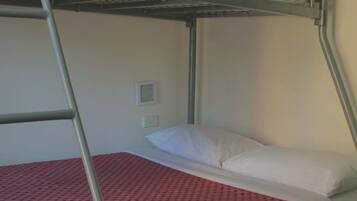 Una cama litera con una escalera, una almohada blanca y una colcha roja con estampado.