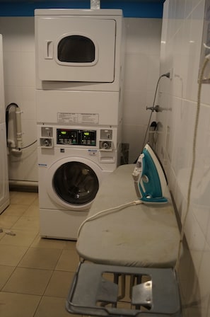 A laundry room with a stacked washer and dryer, an iron, and a utility sink. - 790 on George Backpackers (Haymarket)