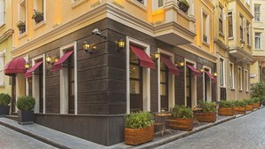 A corner building with large windows, awnings, and outdoor seating with planters. - Meroddi Pera Flats (Istanbul)