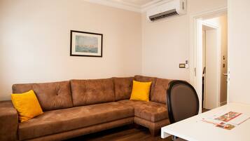 A living room with a brown sectional sofa, a white table, and a framed picture on the wall.