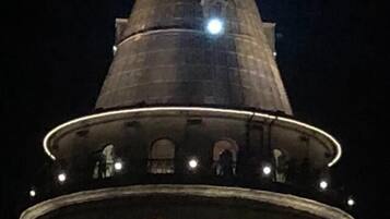 A tower with a conical roof and a circular base with arched windows.