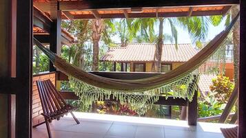 A covered outdoor area with a hammock, wooden benches, and a tiled floor.