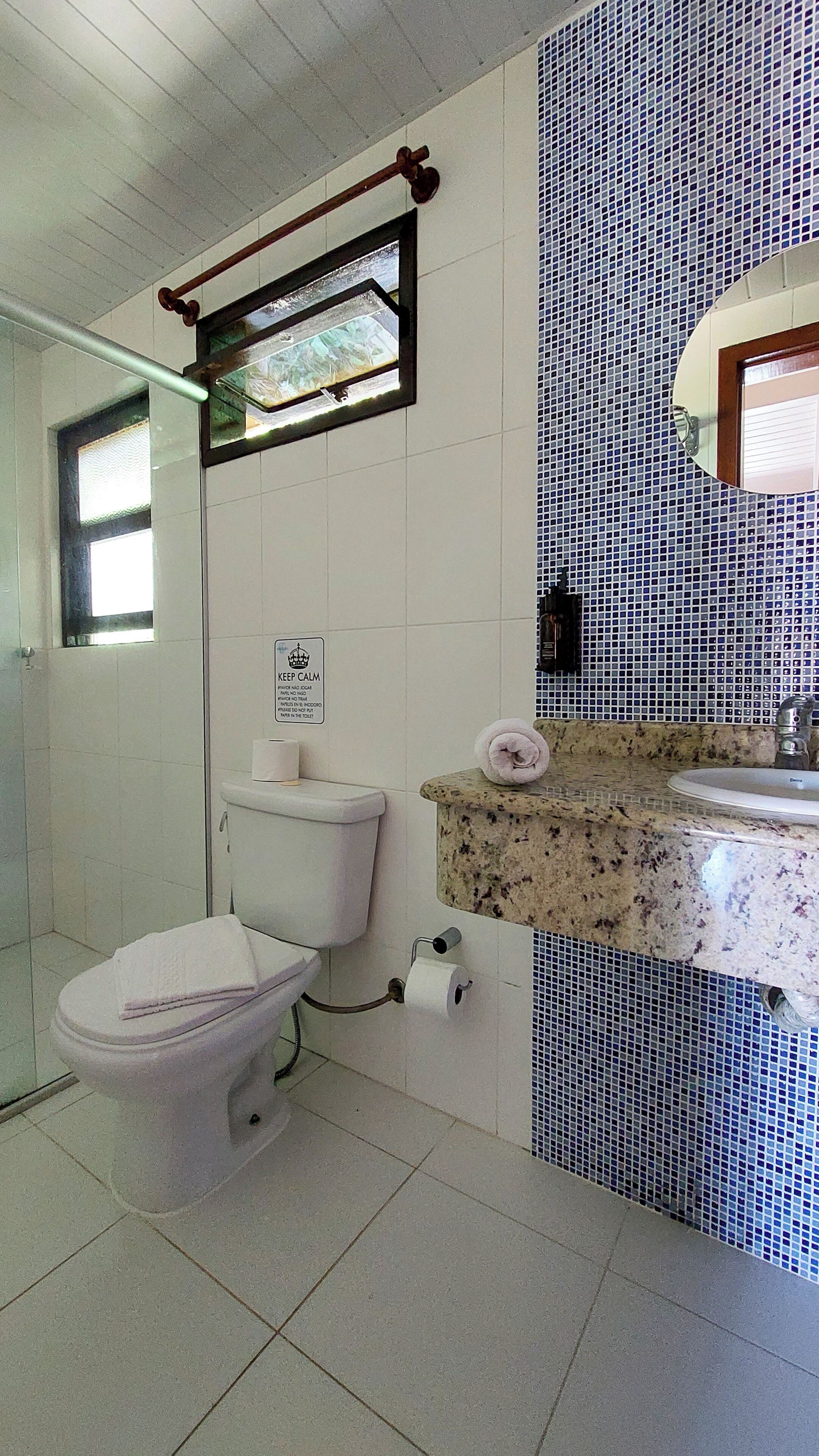 Een badkamer met toilet, wastafel, spiegel en een handdoek op het aanrecht.
