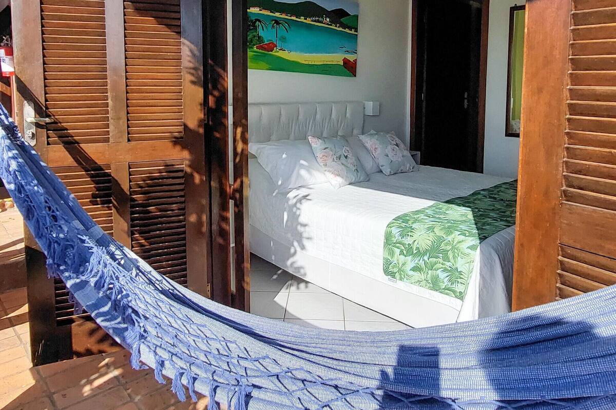 A room with a bed, a hammock, and a painting of a beach scene.