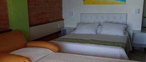 Un dormitorio con cama, sofá, un cuadro en la pared y una pared de ladrillo.