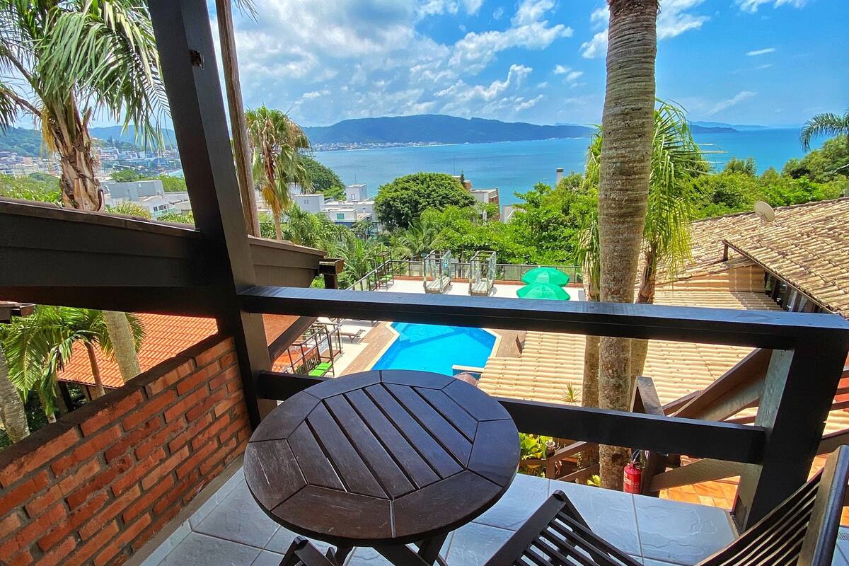 A balcony with a view of the sea, a pool, and a brick wall.