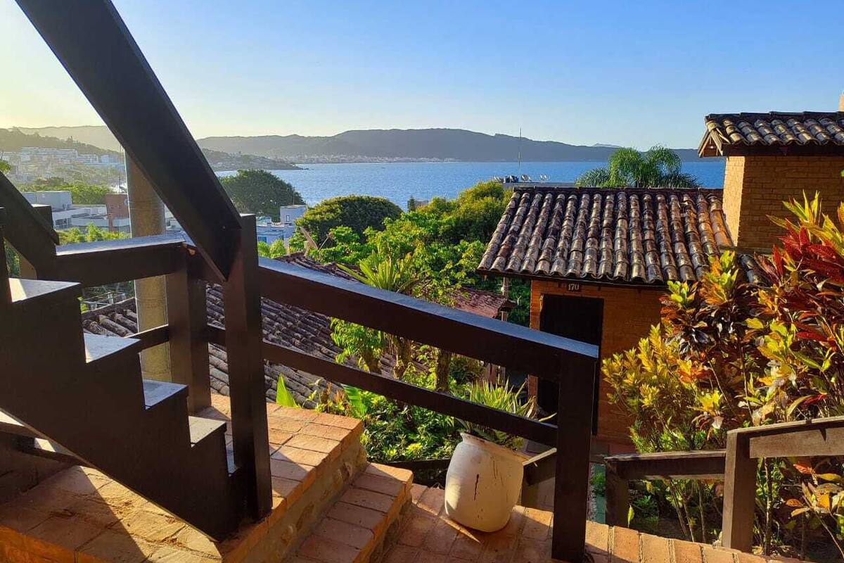 A staircase leading to a terrace with a view of a body of water and hills in the distance.