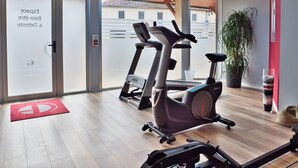 A gym with exercise equipment, a red mat, and a potted plant. - La Table de Gustave (Ornans)