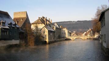 Un pueblo histórico con un río, edificios de piedra y un puente.