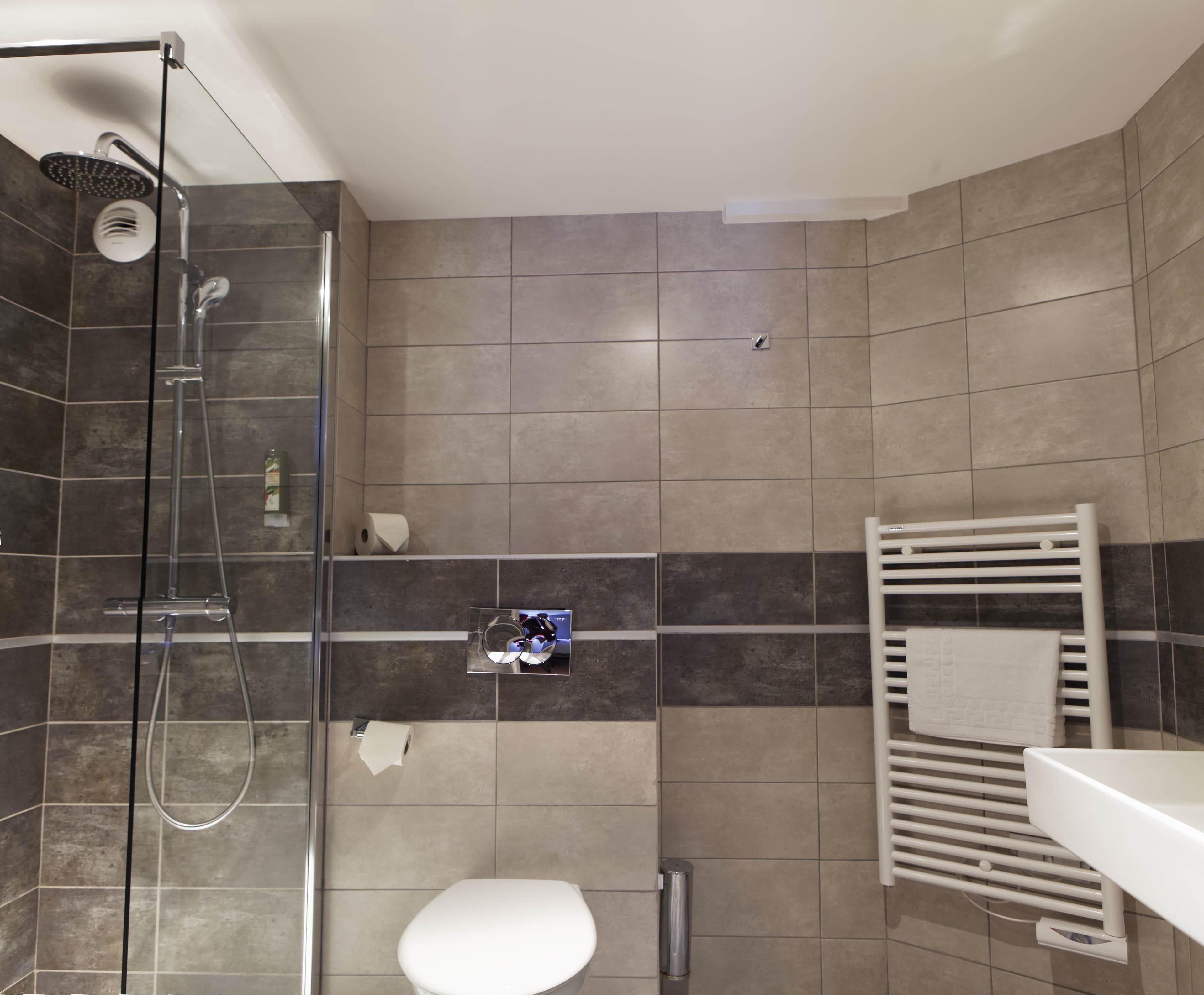 Ein modernes Badezimmer mit einer Duschkabine aus Glas, einer Toilette und einem Handtuchhalter.