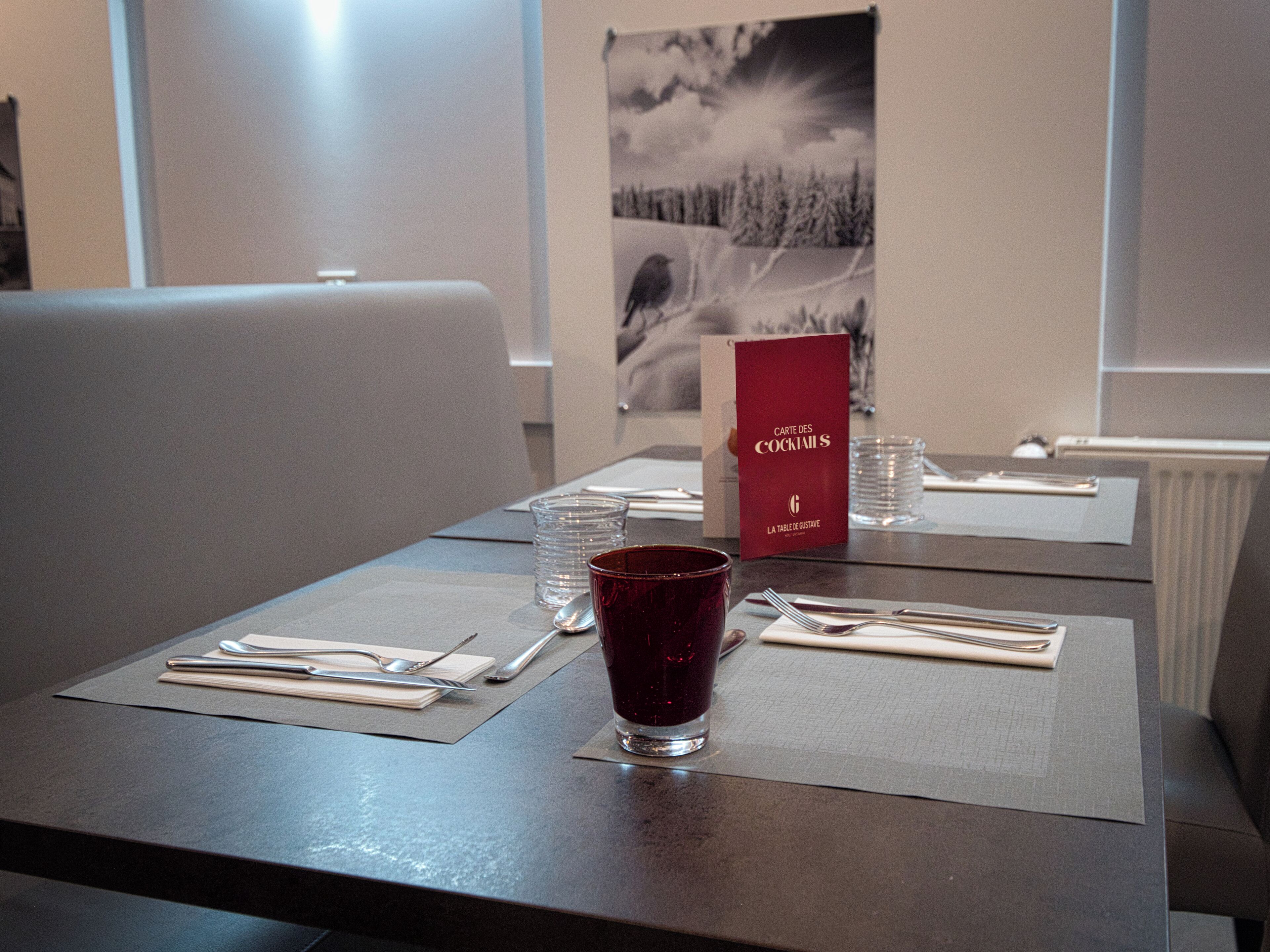 Una mesa de comedor bien puesta, con un menú, vasos y cubiertos.