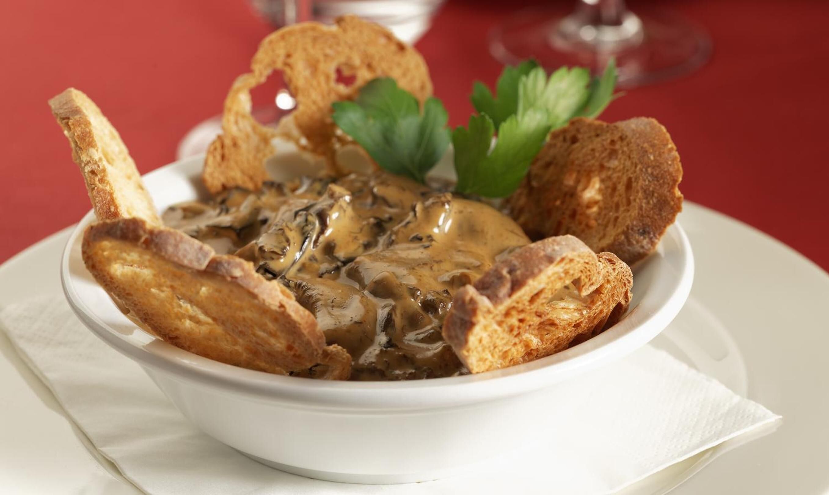 Una ciotola di zuppa di funghi con del pane a fianco.