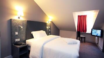A hotel room with a bed, bedside tables, a TV, and a window with red curtains.