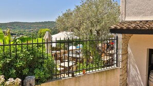 A terrace with outdoor seating, a view of the countryside, and a stone wall. - Hotel Perla Riviera (Cagnes-sur-Mer)