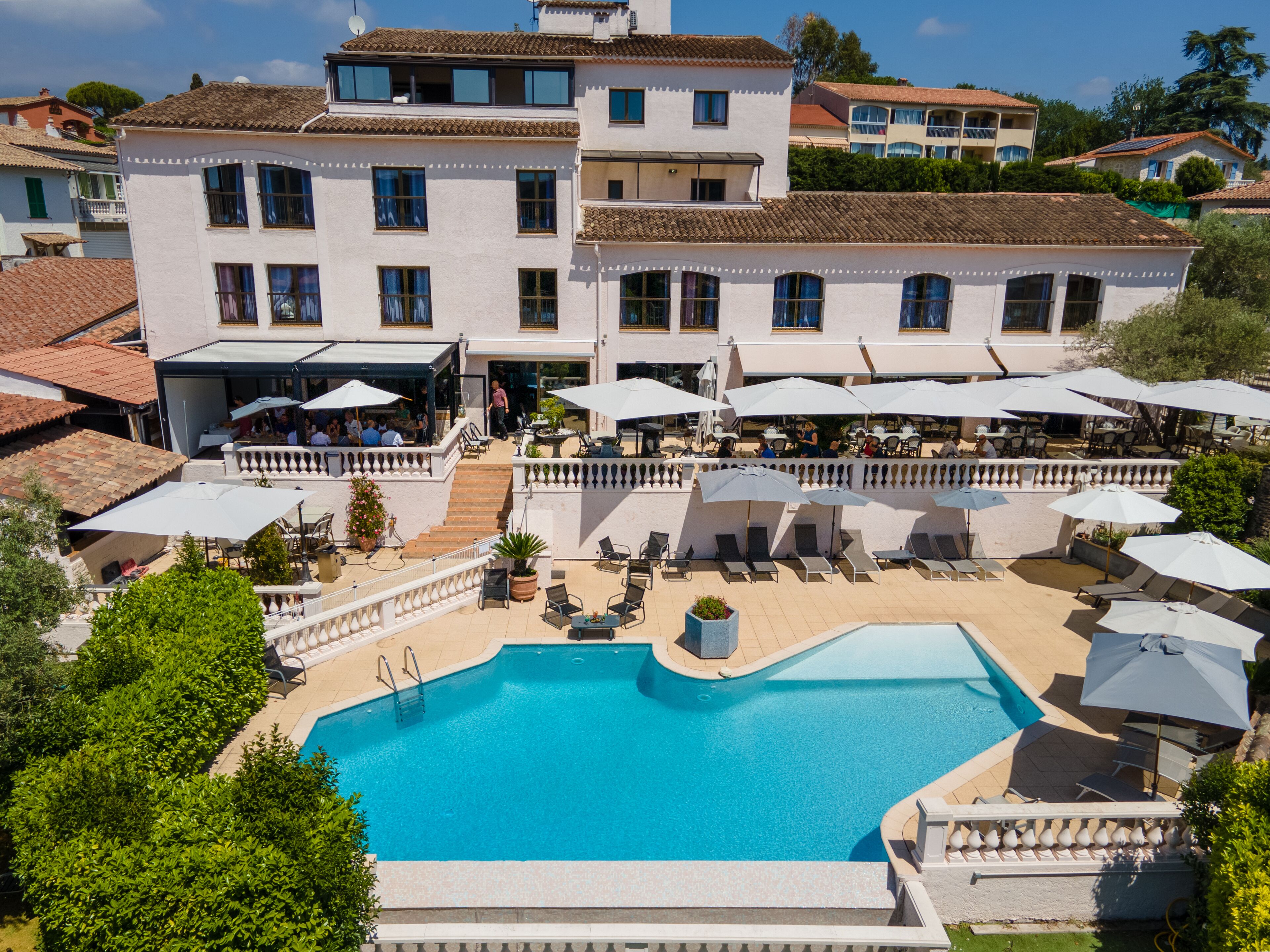 Un edificio grande con piscina, zona de estar exterior y patio cubierto.