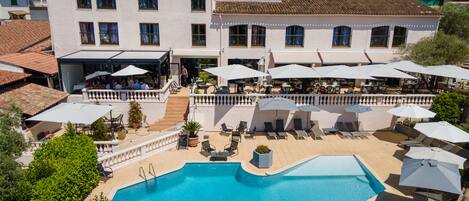 Un edificio grande con piscina, zona de estar exterior y patio cubierto.