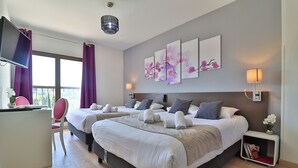 A modern hotel room with two beds, a desk, and a TV. - Hotel Perla Riviera (Cagnes-sur-Mer)