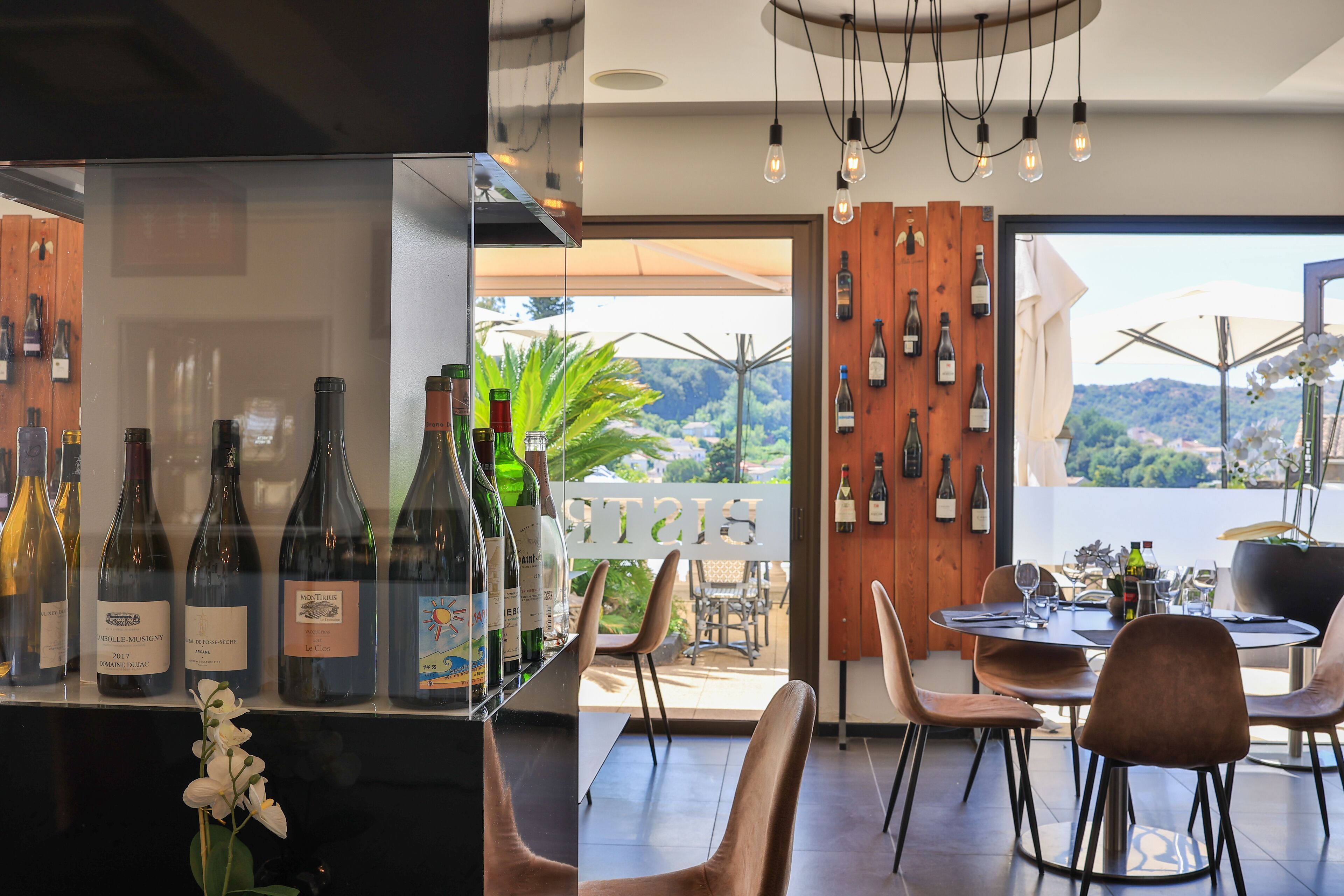 Un espace bar moderne avec des bouteilles de vin, une table à manger et des chaises.