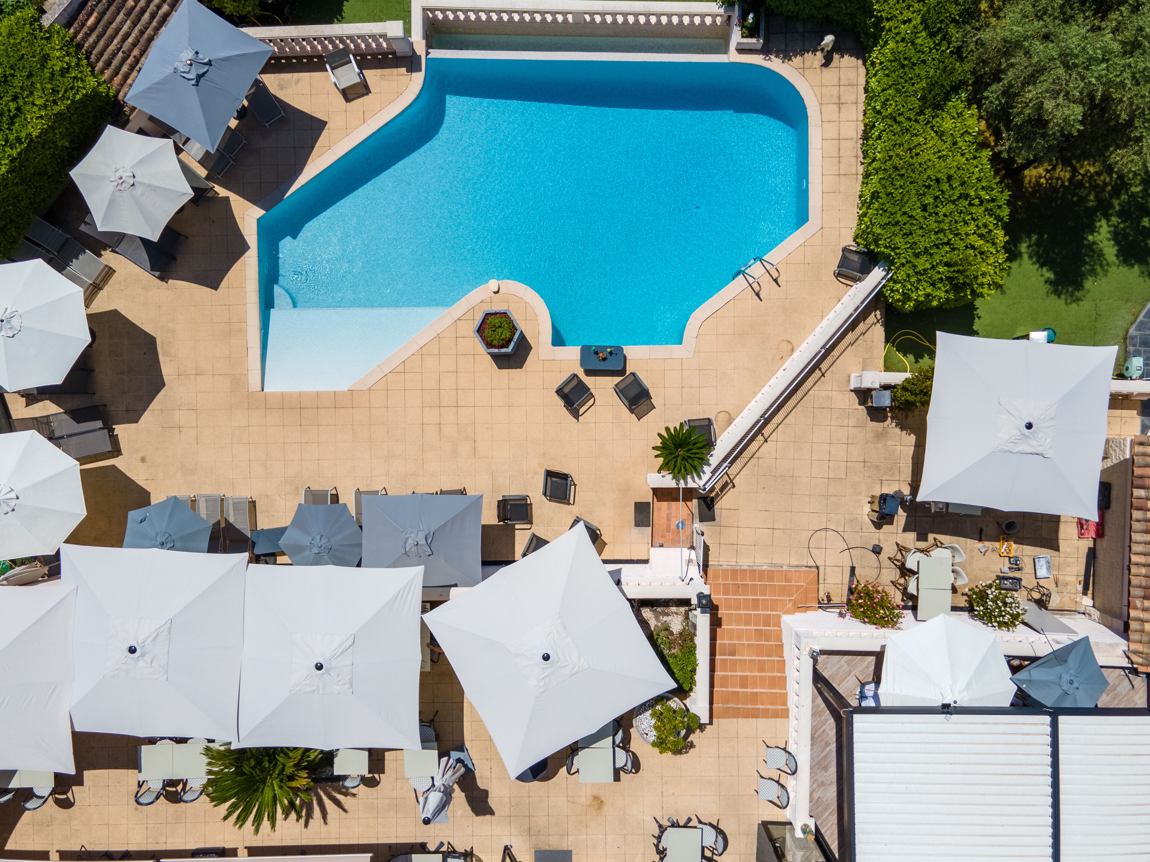 An aerial view of a swimming pool area with multiple lounge chairs and umbrellas.