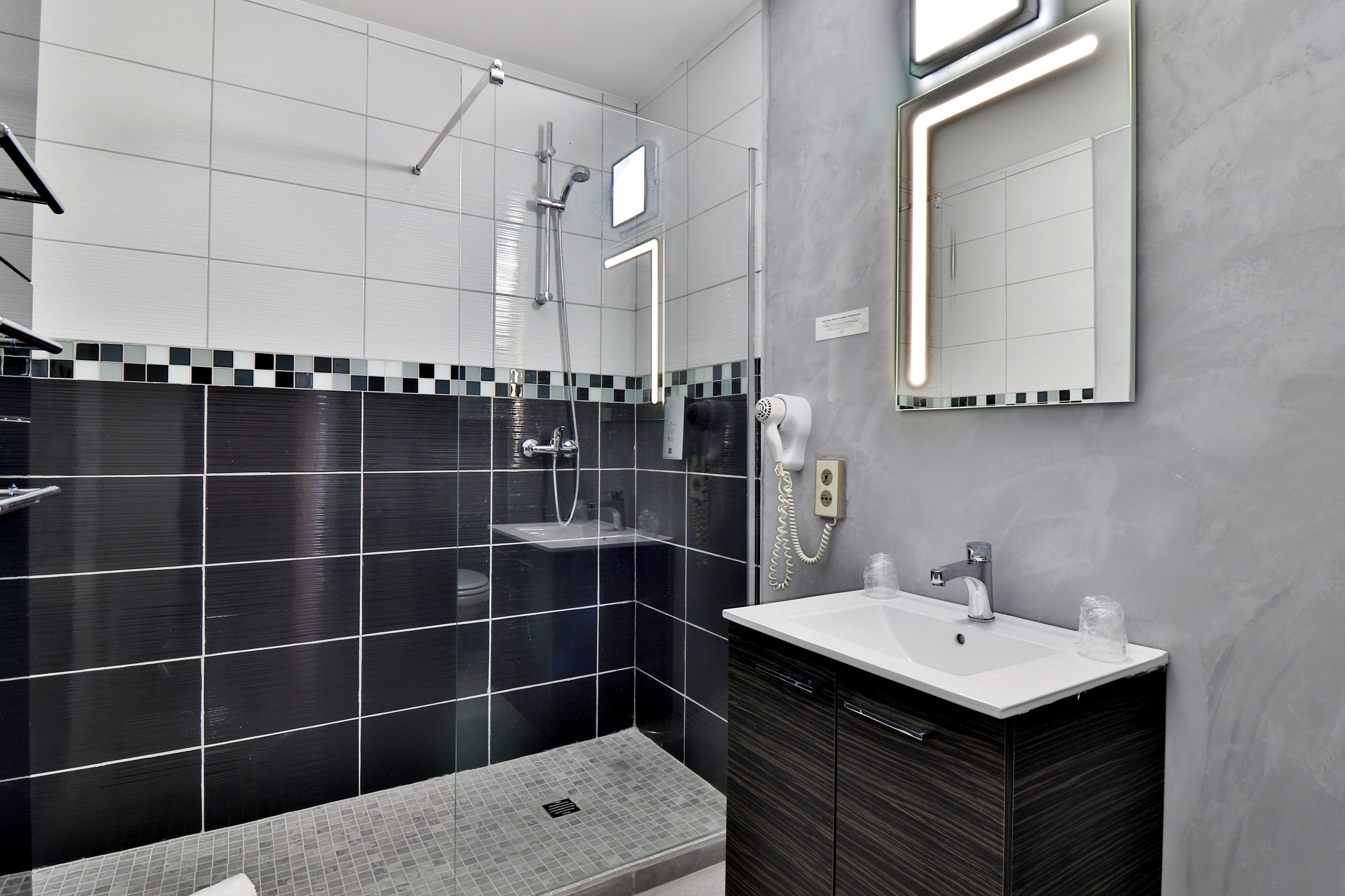 A modern bathroom with a large mirror, a sink, and a shower area.