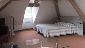 A bedroom with a bed, a desk, and a chair. There is a window and a radiator. - Hôtel Fifi Moulin (Serres)