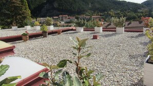 A rooftop terrace with potted plants and a view of a mountainous landscape. - Hôtel Fifi Moulin (Serres)