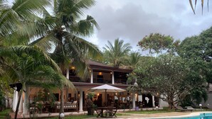 A poolside area with a pool, lounge chairs, and a covered seating area with tables and umbrellas. - Kenyan House Malindi (Malindi)