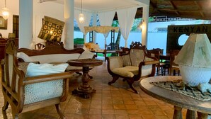 A cozy lounge area with wooden furniture, a round table, and a view of the sea. - Kenyan House Malindi (Malindi)