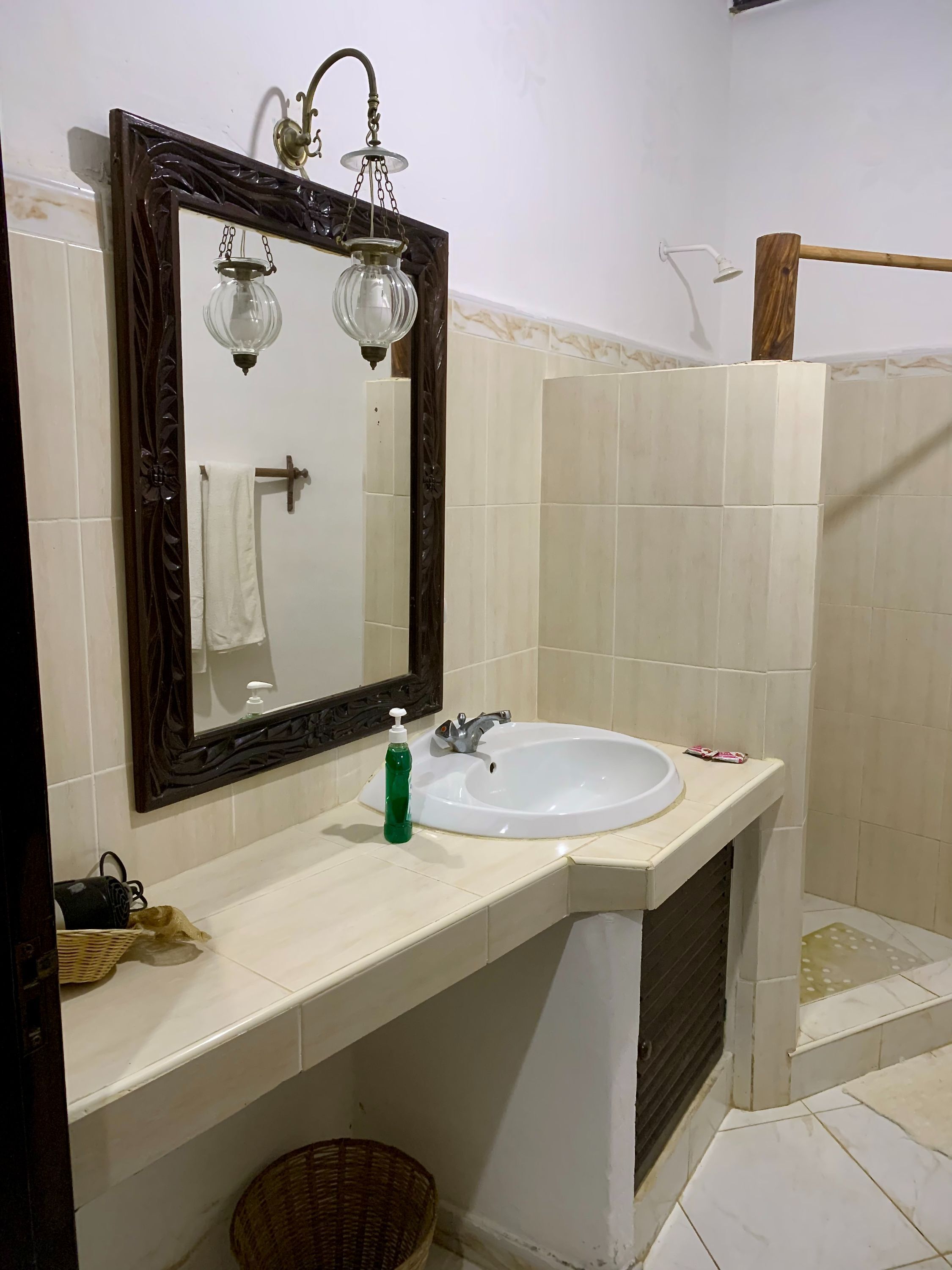 Un baño con un lavabo blanco, un espejo con un marco decorativo y una zona de ducha.