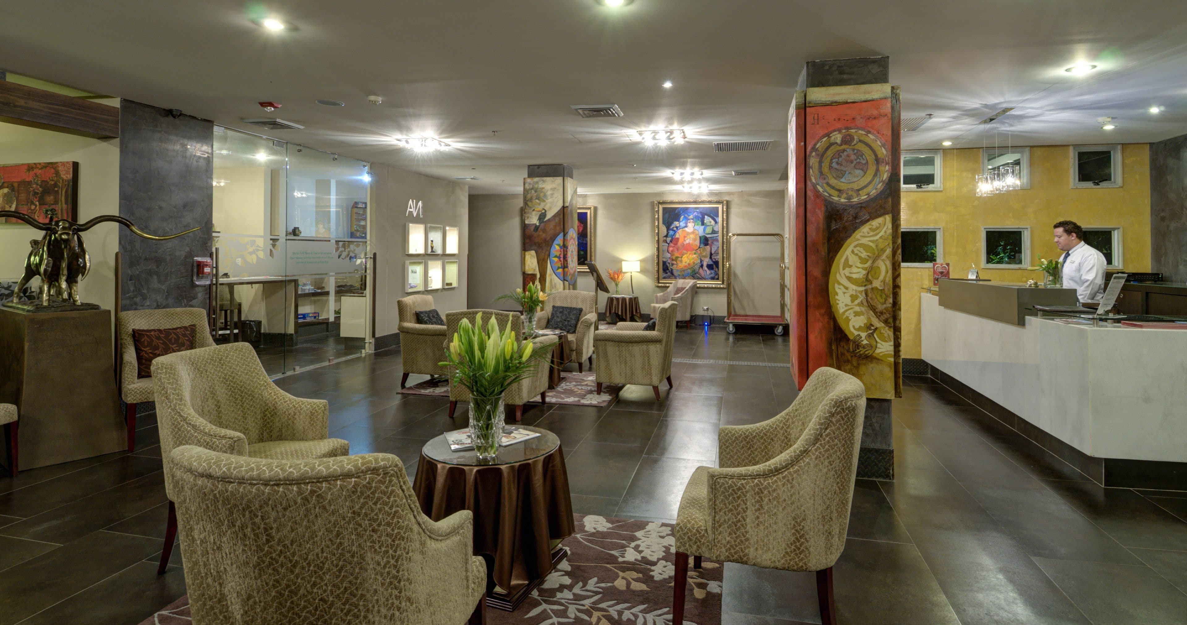A hotel lobby with seating areas, a reception desk, and artwork on the walls.