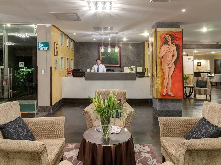A hotel lobby with a reception desk, two sofas, a coffee table, and a large painting.