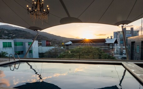 A swimming pool with a view of a sunset and buildings in the background.