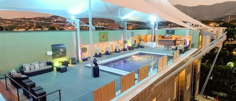 A rooftop pool area with a bar, seating, and a view of the city.