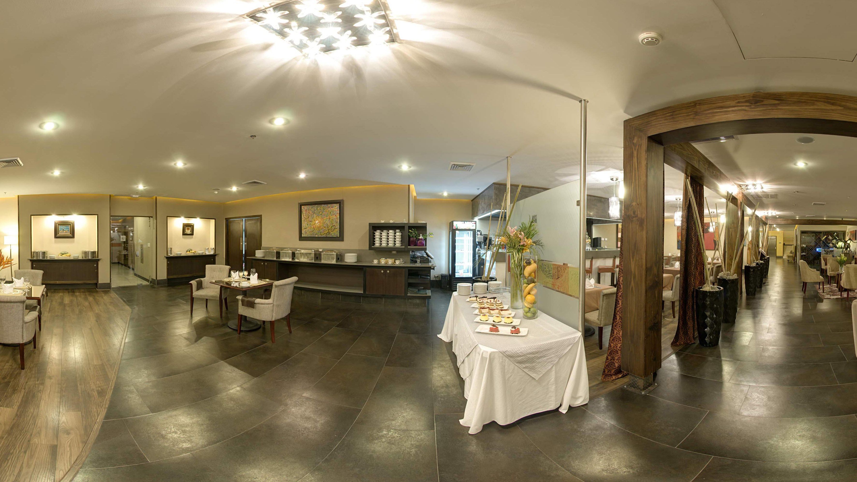 Un amplio vestíbulo de hotel con mostrador de recepción, zona de estar y mesa de buffet.