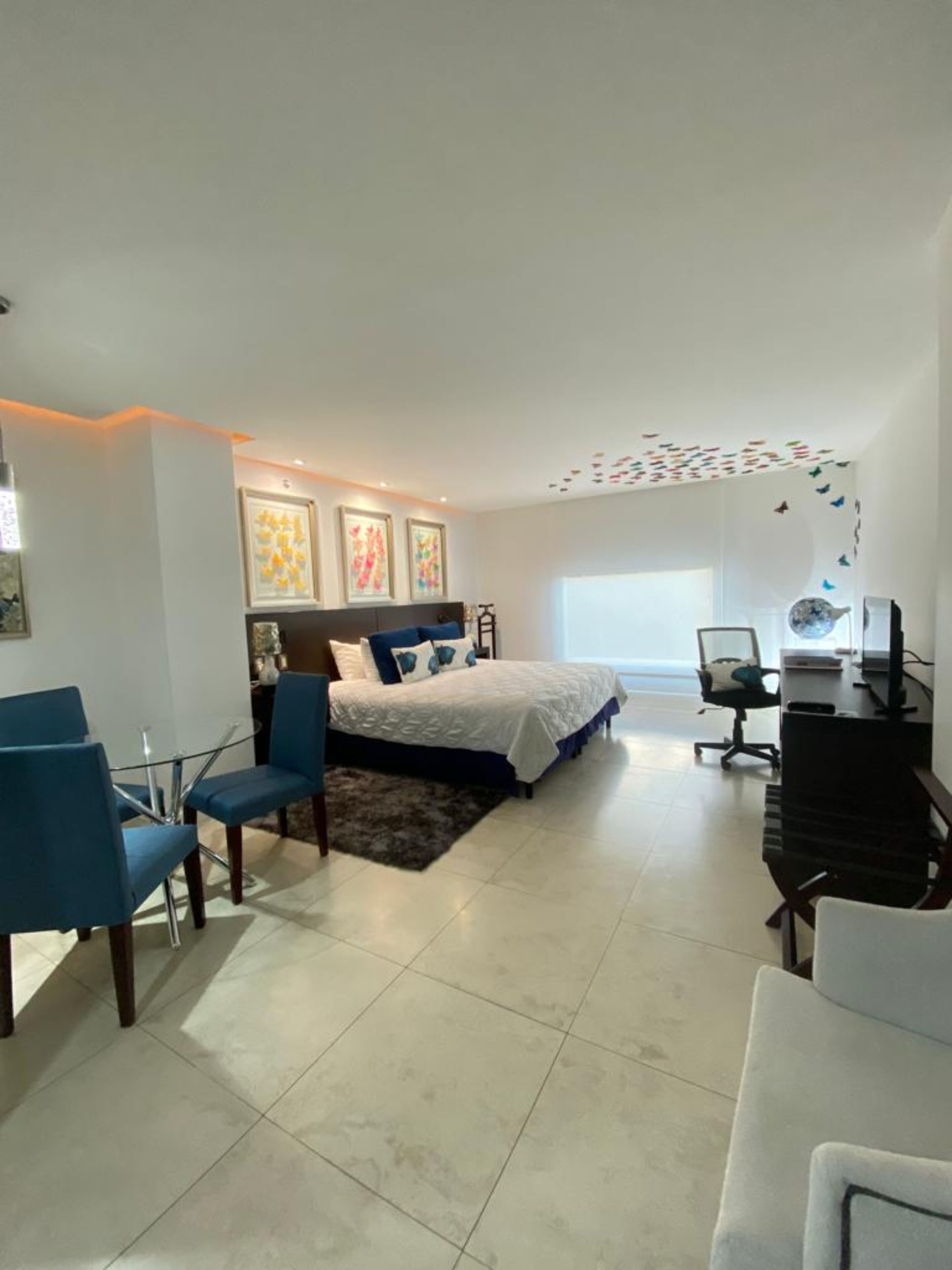 A modern bedroom with a bed, a desk, and two chairs.