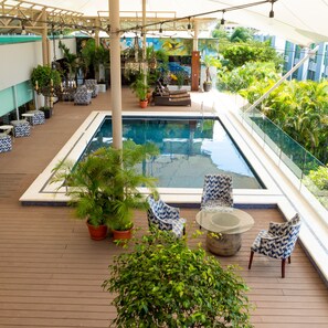 A poolside area with a rectangular pool, lounge chairs, potted plants, and a view of the surrounding greenery. - Studio Hotel Boutique (Santa Ana)