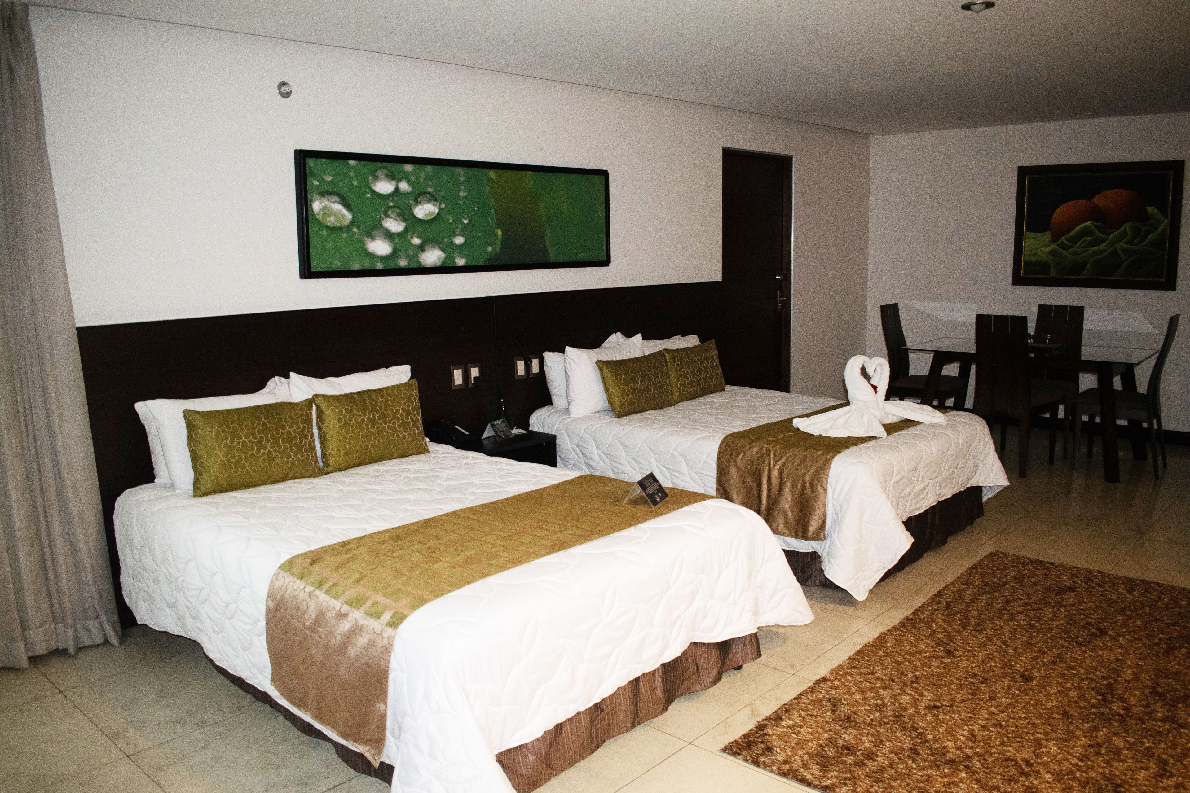 A hotel room with two beds, a dining table, and chairs.