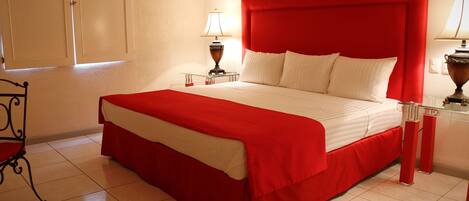 Una habitación de hotel con una cama grande, una mesita de noche, una lámpara, una silla y un armario.
