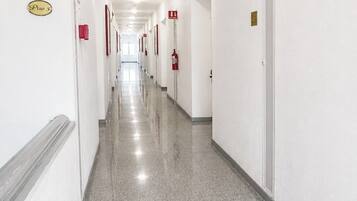 A long, narrow hallway with white walls, doors on both sides, and a polished floor.