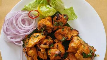 A plate of chicken tikka with lettuce and sliced onions.