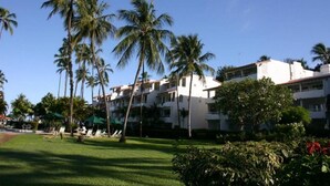 A hotel with multiple floors, palm trees, and a well-maintained lawn. - Glitter Bay (Holetown)