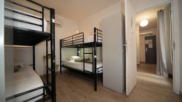 Un dormitorio con literas, una mesita pequeña y una puerta que da a otra habitación.
