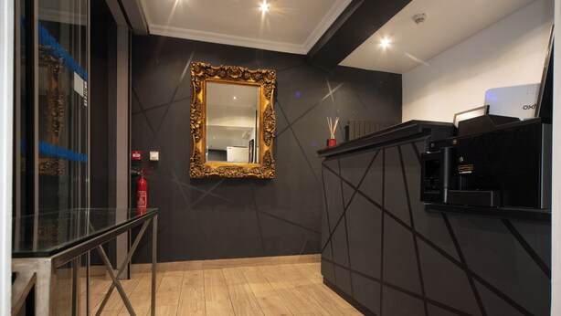 A modern kitchen with a large mirror, a glass railing, and a black countertop. - Enjoy Hostel (Paris)
