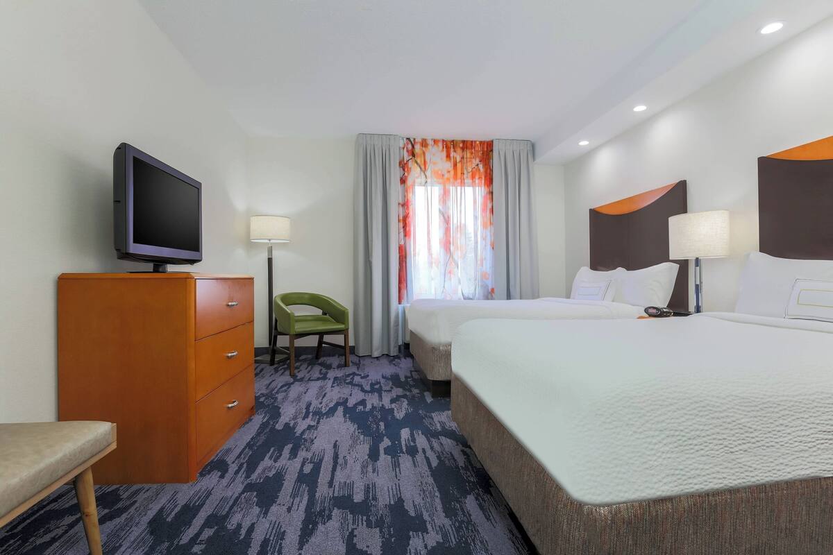 Een hotelkamer met een bed, een televisie, een bureau en een stoel.
