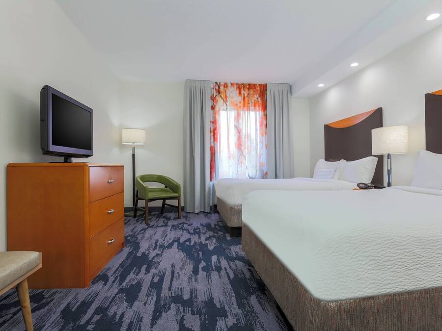 Une chambre d’hôtel avec un lit, une télévision, un bureau et une chaise.