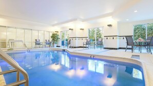 An indoor swimming pool with clear water, surrounded by lounge chairs and a glass wall. - Fairfield Inn & Suites Mahwah (Mahwah)