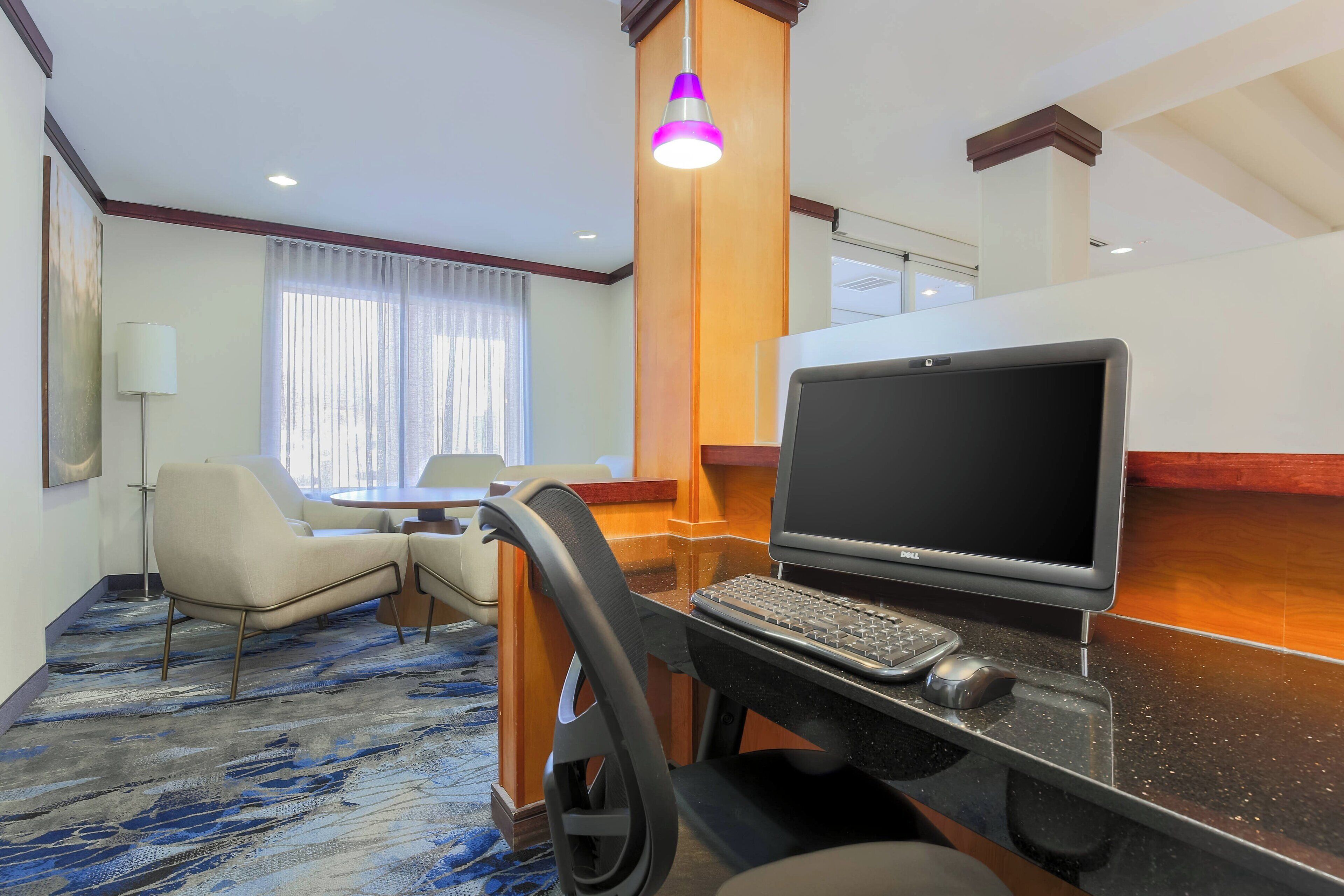 Een hotelkamer met een bureau, laptop en stoel.