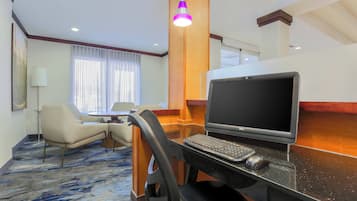 Een hotelkamer met een bureau, laptop en stoel.