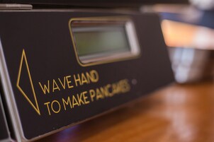 A close-up of a device with the text "WAVE HAND TO MAKE PANCAKES."